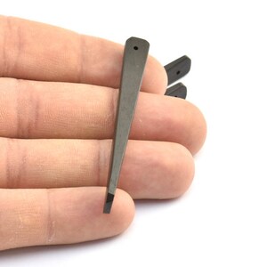 May include: Three black plastic guitar picks with a pointed tip. The picks are held in a hand.