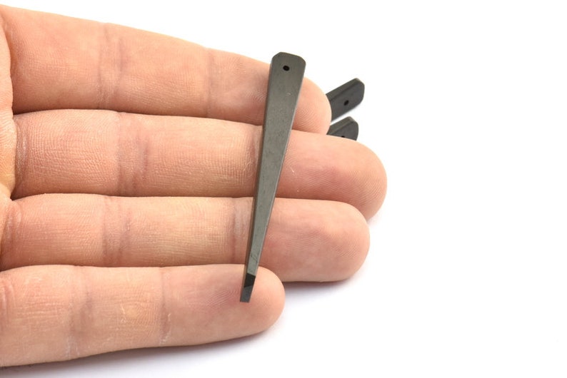 May include: Three black plastic guitar picks with a pointed tip. The picks are held in a hand.
