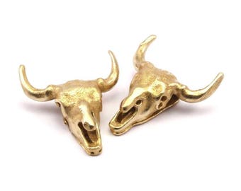 May include: Two gold-colored metal bull skull charms. The skulls are detailed and have a textured finish.