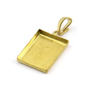 May include: A gold-toned metal pendant with a rectangular frame and a bail for attaching a chain. The frame has a decorative border.