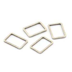 May include: Four silver-toned metal jump rings, each with a rectangular shape. The rings are arranged in a loose cluster on a white background.