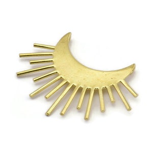May include: Gold-toned metal sun and moon charm with a crescent moon shape and sun rays emanating from the bottom of the moon.