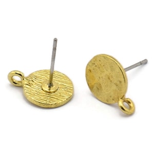 Puede incluir: Dos bases de pendientes de color dorado con una superficie redonda texturizada y un pequeño bucle en el lateral. Cada base tiene un poste plateado y una parte posterior.