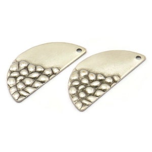 May include: Two silver half-circle metal charms with a textured design. The charms have a hole at the top for attaching to jewelry or other crafts.