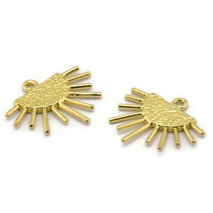 May include: Two gold-toned metal charms shaped like a half-circle with radiating lines. The charms have a textured surface and a loop for attaching to jewelry.