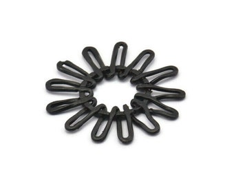 Könnte beinhalten: Ein schwarzer Haargummi aus Kunststoff mit einem einzigartigen Design, das an eine Blume erinnert. Der Haargummi besteht aus mehreren ineinandergreifenden Schlaufen, die eine kreisförmige Form bilden.