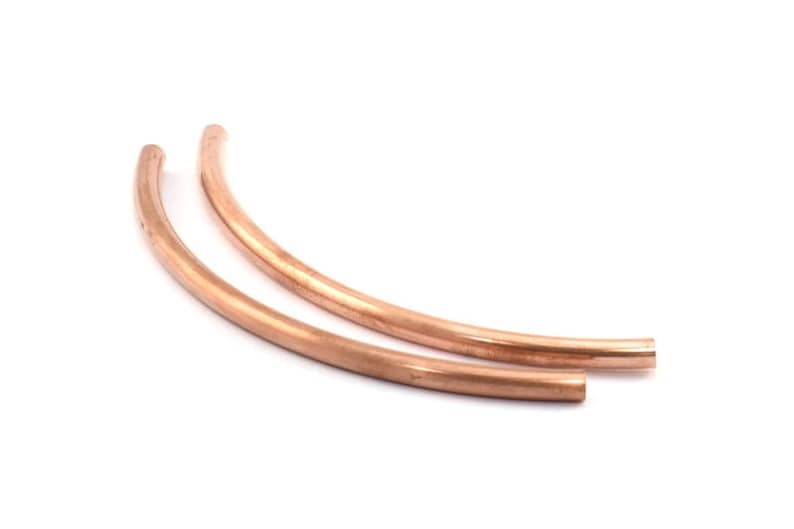 May include: Two copper pipe segments, each bent into a gentle arc, are arranged side-by-side. The pipes are a warm, reddish-brown color and have a smooth, polished finish.