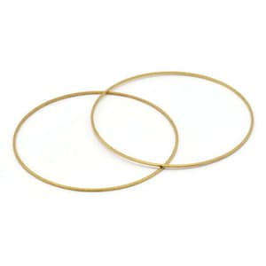 Puede incluir: Dos aros de metal de color dorado, uno ligeramente más grande que el otro, están entrelazados.