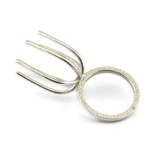 Könnte beinhalten: Silberne Ringfassung mit runder, verzahnter Oberseite und einem strukturierten Band.
