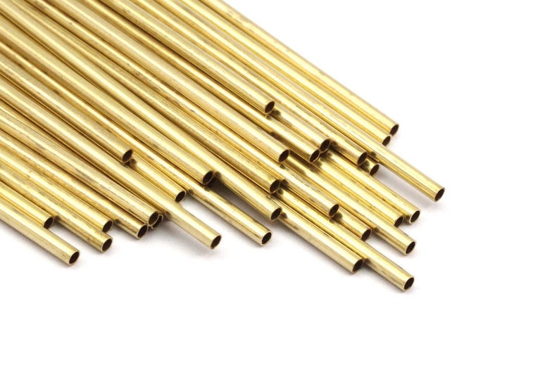 May include: A pile of gold-colored brass tubing, arranged in a fan shape. The tubing is smooth and shiny, with a slightly rounded edge.