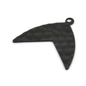 Könnte beinhalten: Schwarzer Metallanhänger in Form eines Boomerangs mit gehämmerter Textur.