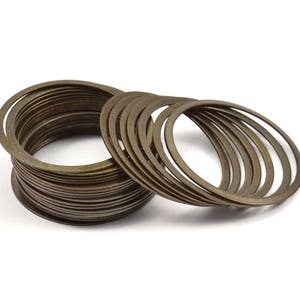 May include: A stack of 18 gold-toned metal rings, some stacked on top of each other and some lying flat.