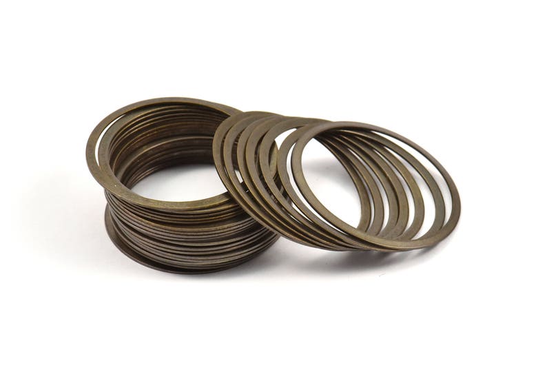 May include: A stack of 18 gold-toned metal rings, some stacked on top of each other and some lying flat.