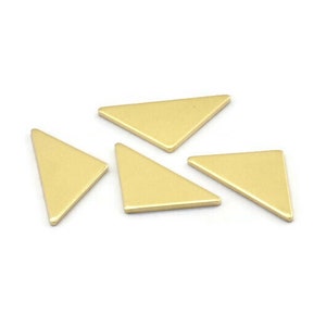 Puede incluir: Cinco piezas metálicas de forma triangular de color dorado. Las piezas están dispuestas en un patrón aleatorio sobre una superficie blanca.
