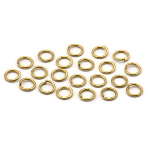 Könnte beinhalten: Eine Gruppe von 20 goldenen Sprungringen, eine Art von Schmuckzubehör, liegt auf einem weißen Hintergrund.