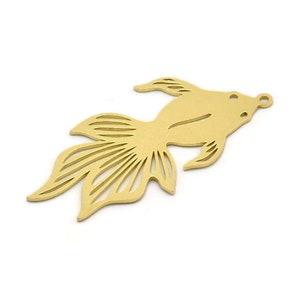 Può includere: Ciondolo in metallo color oro a forma di pesce con un design dettagliato. Il ciondolo ha un foro nella parte superiore per essere attaccato a una collana o un braccialetto.