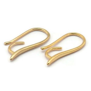May include: A pair of gold-toned earring hooks. The hooks are made of a smooth, curved metal and have a simple, elegant design.