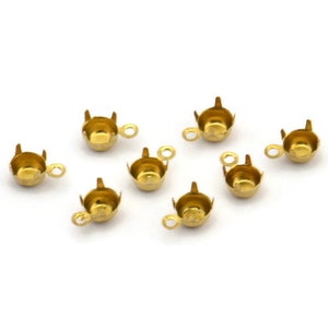 May include: Eight gold-toned metal cup settings with a loop on the side. The cups are designed to hold a round cabochon stone.