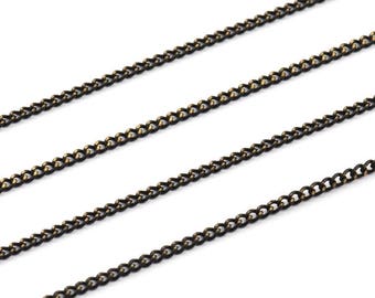 May include: Three strands of black chain with a gold undertone. The chain is a curb style with a flat, rectangular link.