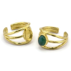May include: Two gold adjustable rings with a textured finish. One ring has a green oval stone set in the center. The other ring has a blank setting.