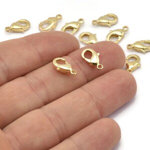 Peut inclure: Gros plan sur un groupe de fermoirs &agrave; ressort en m&eacute;tal dor&eacute;. Les fermoirs sont petits et d&eacute;licats, et ils sont parfaits pour ajouter une touche d'&eacute;l&eacute;gance aux bijoux.