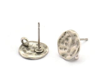 May include: A pair of silver-toned earring posts with a textured, round disc design. The posts are made of metal and have a loop on the back for attaching to earrings.