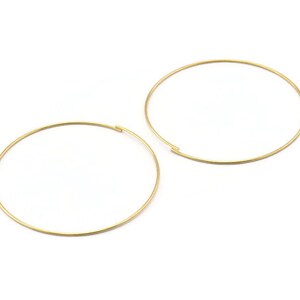 Könnte beinhalten: Zwei goldene Creolen. Die Creolen sind einfach und rund.