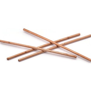 Puede incluir: Cuatro tubos de cobre, de aproximadamente 30 cm de largo, dispuestos en forma de cruz sobre un fondo blanco.