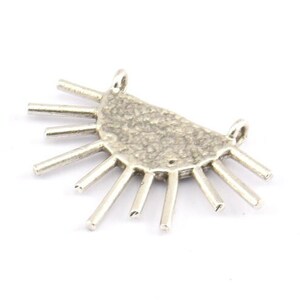 May include: Silver pendant with a half-circle design and radiating spikes. The pendant has a textured surface.