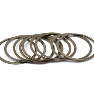 May include: A set of ten bronze-colored metal washers. The washers are stacked on top of each other and are arranged in a circle.