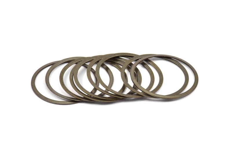 May include: A set of ten bronze-colored metal washers. The washers are stacked on top of each other and are arranged in a circle.