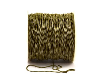 May include: A spool of olive green chain with small round beads. The chain is wound around a white spool and a small section of the chain is hanging down.