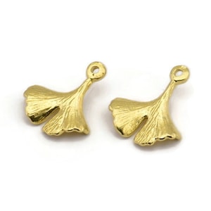 May include: Two gold-tone ginkgo leaf charms with a loop at the top for attaching to jewelry or other crafts.