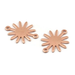 May include: Two rose gold metal sunburst charms with two jump rings each. The charms are round with a sunburst design and have a smooth, shiny finish.