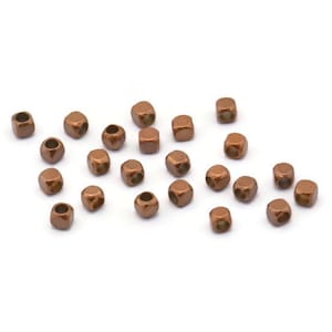 Peut inclure: Une dispersion de petites perles métalliques de couleur cuivre, chacune de forme carrée et avec un trou au centre.