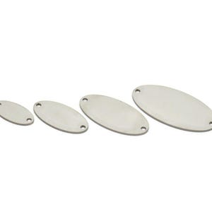 Op de afbeelding: Vier zilveren ovale metalen labels in verschillende maten met elk twee gaten.