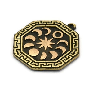 May include: A gold-toned octagonal pendant with a black background and a design of a star surrounded by eight crescent moons and a sun. The pendant has a decorative border with a repeating geometric pattern.