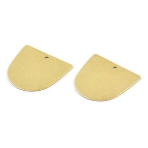 May include: Two gold-colored metal half-circle shapes with a hole in the top. The shapes are slightly textured.