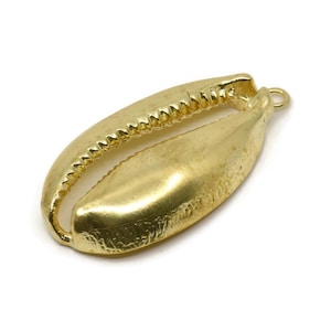 May include: A gold-colored cowrie shell pendant with a textured edge and a smooth, polished surface. The shell has a loop for attaching to a necklace or bracelet. The pendant is set against a white background.