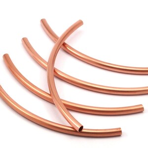 May include: Five copper wire hoops, each bent into a semi-circle shape. The hoops are stacked on top of each other, with the largest hoop at the bottom and the smallest hoop at the top.