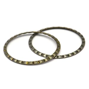 Puede incluir: Dos anillos de metal de color dorado con un borde texturizado y acanalado. Los anillos están entrelazados.