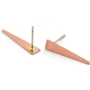 Puede incluir: Un par de pendientes de triángulo de cobre con poste de plata y respaldo dorado.