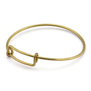 Puede incluir: Un brazalete expandible de color dorado con un diseño simple y minimalista.