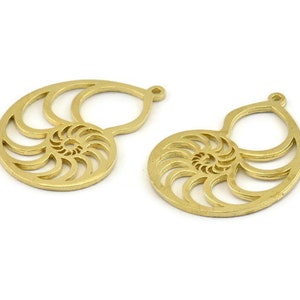 May include: Two gold-colored metal nautilus shell charms with a cutout design. The charms have a hole at the top for attaching to jewelry.