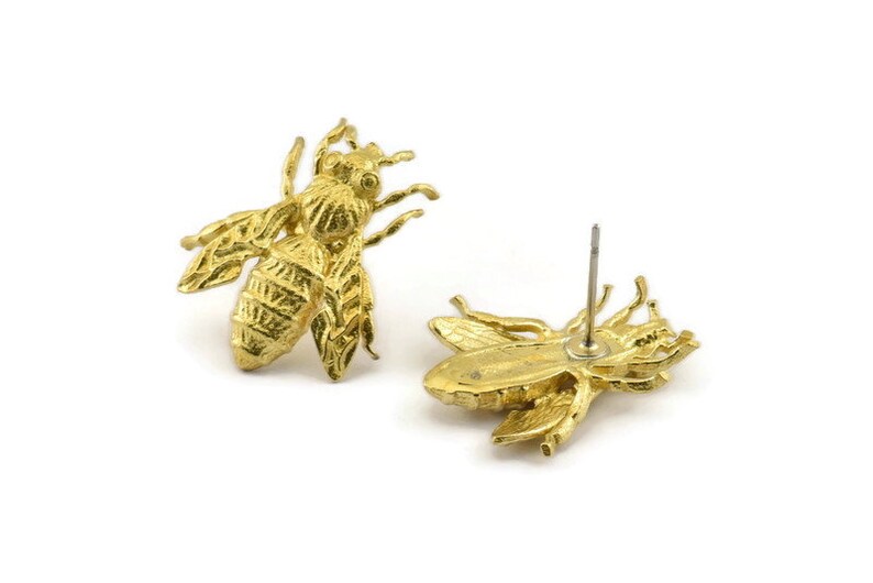 May include: A pair of gold bee stud earrings. The bee is detailed with textured wings and a body.