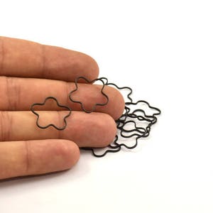 May include: A pile of black metal star-shaped rings, held in a hand.