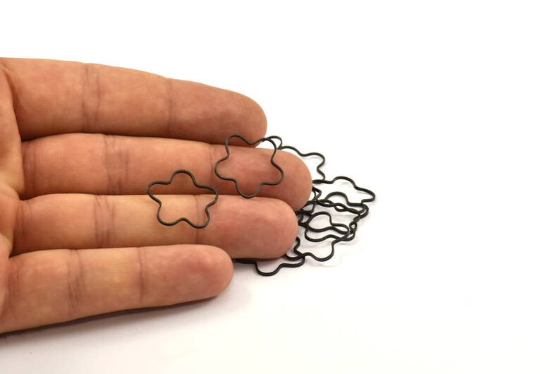May include: A pile of black metal star-shaped rings, held in a hand.