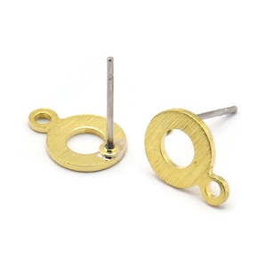 Puede incluir: Un par de hallazgos de pendientes de tono dorado con un diseño circular y un pequeño bucle en el lateral. Los hallazgos tienen un poste y un cierre de mariposa.