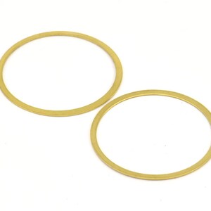 May include: Two gold-colored metal rings, one larger than the other, are shown against a white background.