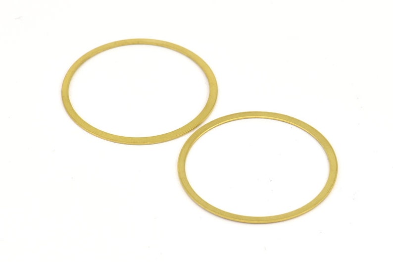 May include: Two gold-colored metal rings, one larger than the other, are shown against a white background.
